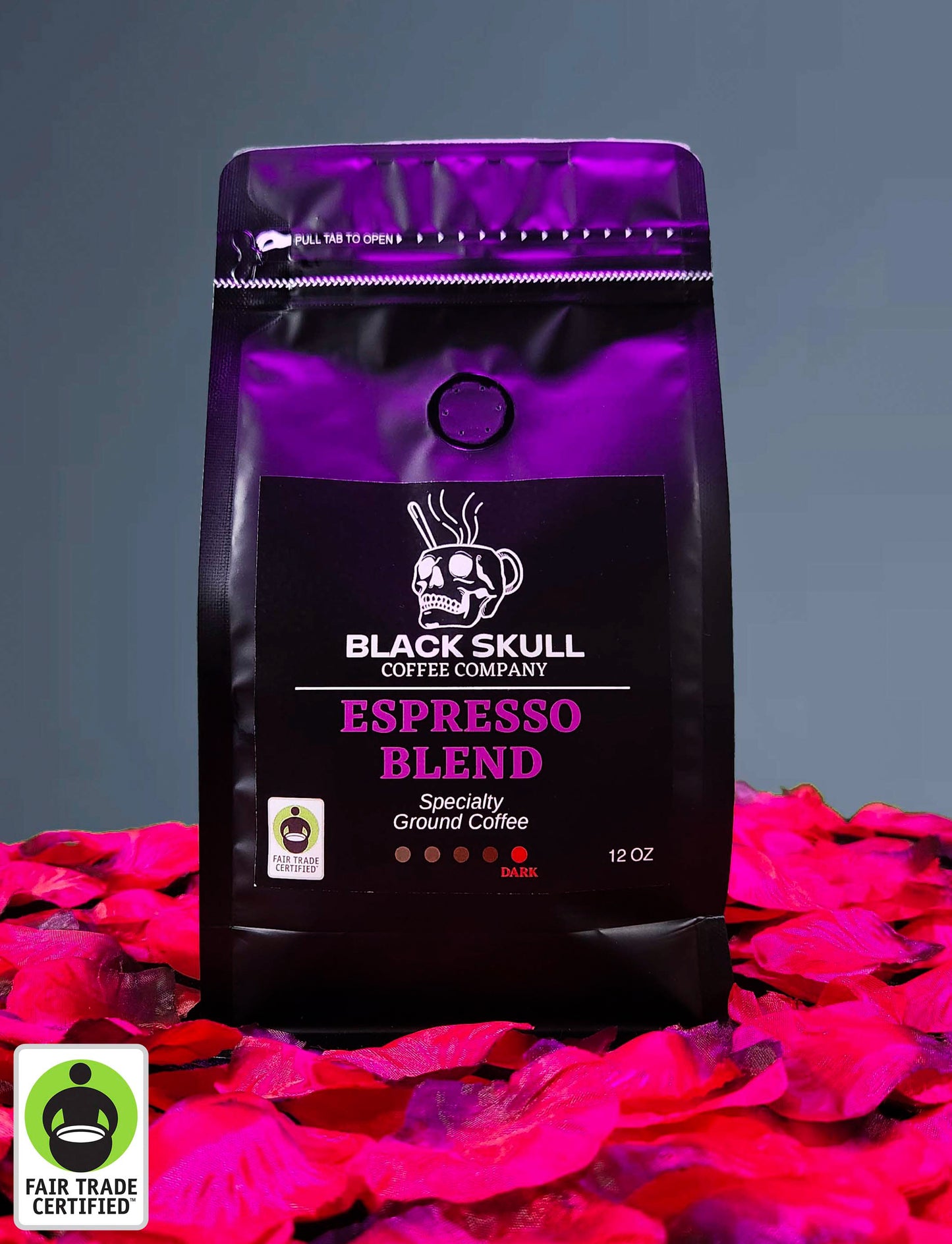 Black Skull Coffee Company Specialty Espresso Blend 12oz ground coffee package on a gray background with red rose petals and Fair Trade USA Logo.