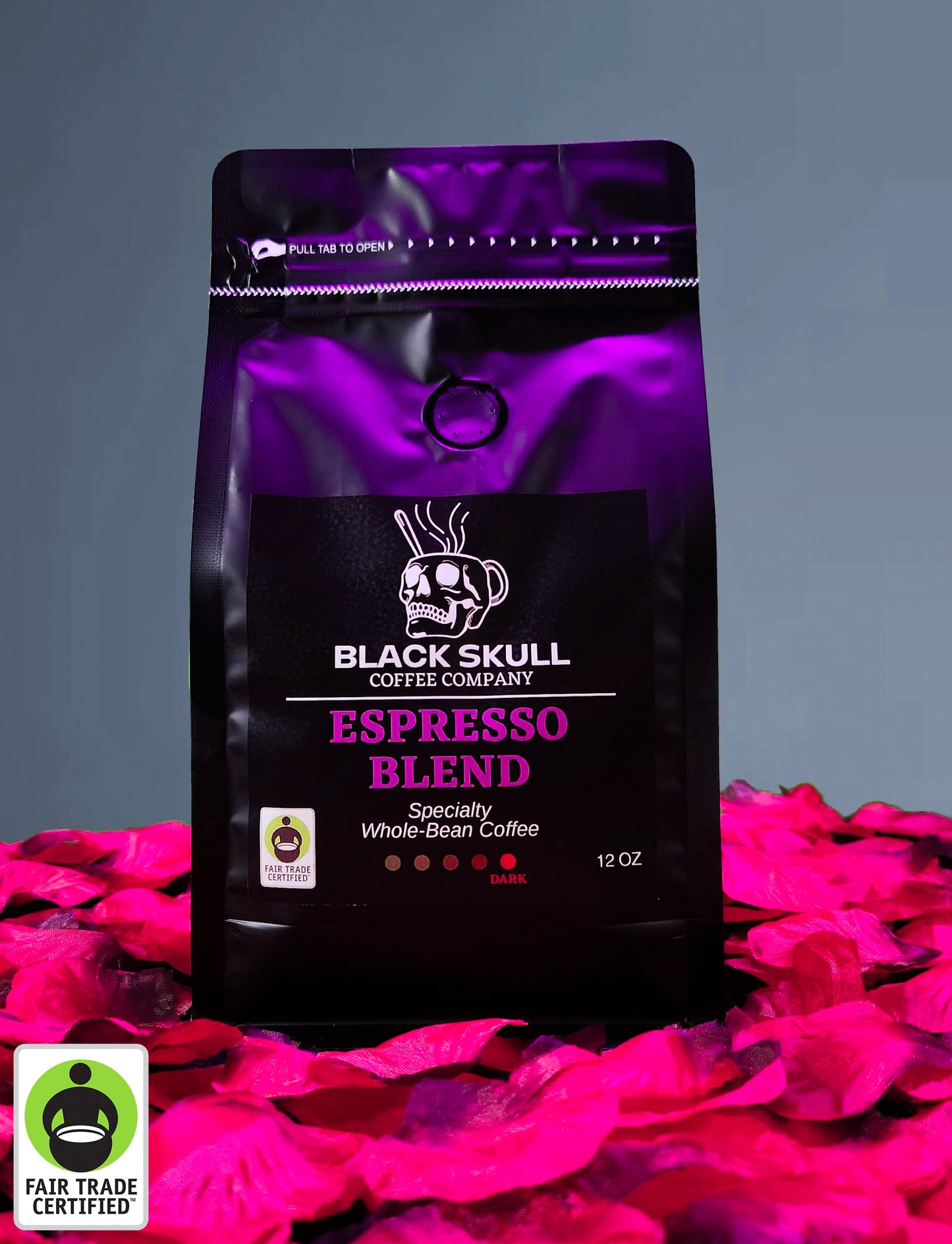 Black Skull Coffee Company Specialty Espresso Blend 12oz whole bean coffee package on a gray background with red rose petals and Fair Trade USA Logo.