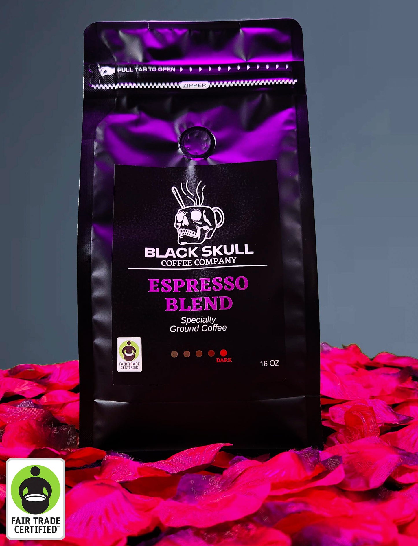 Black Skull Coffee Company Specialty Espresso Blend 16oz ground coffee package on a gray background with red rose petals and Fair Trade USA Logo.
