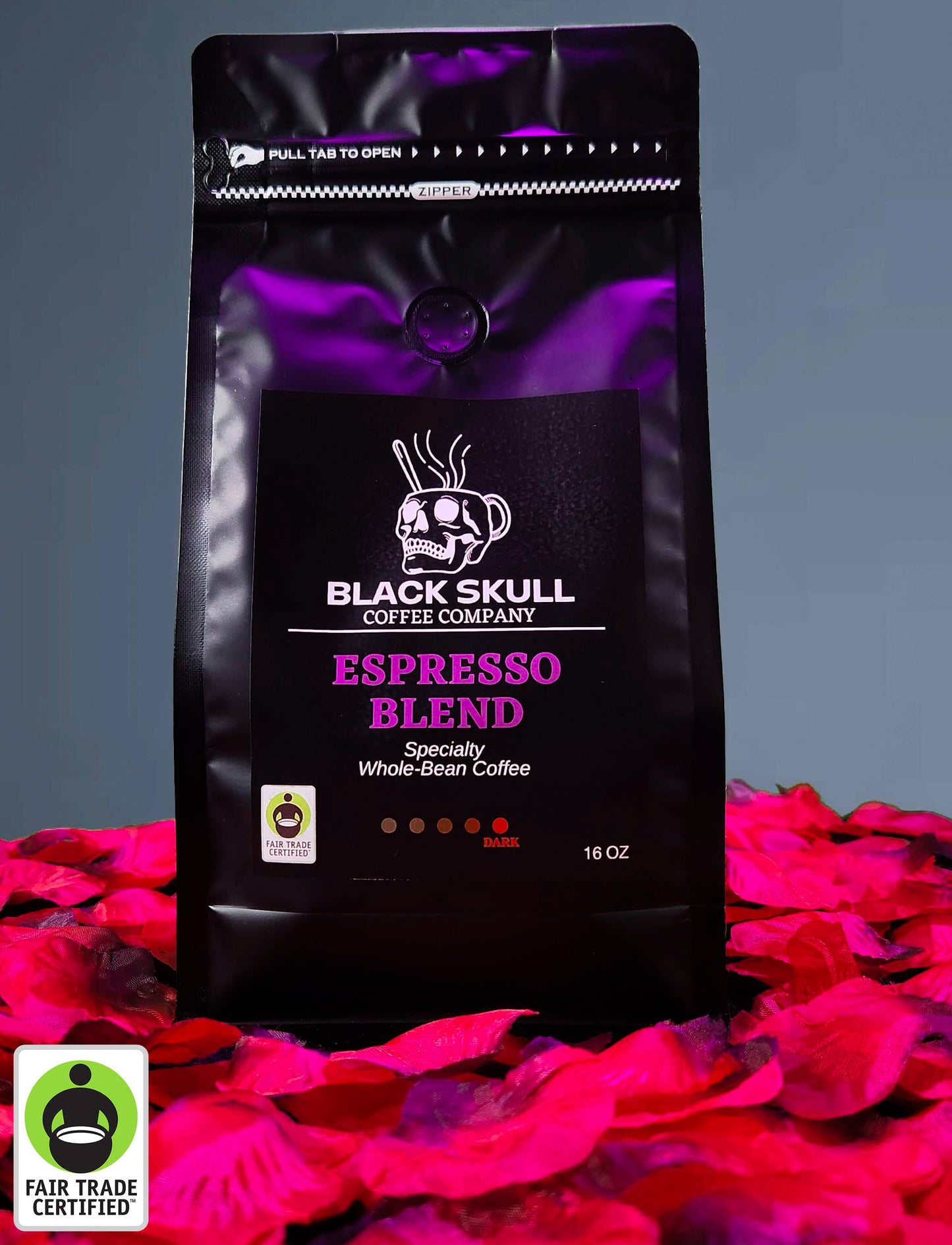 Black Skull Coffee Company Specialty Espresso Blend 16oz whole bean coffee package on a gray background with red rose petals and Fair Trade USA Logo.