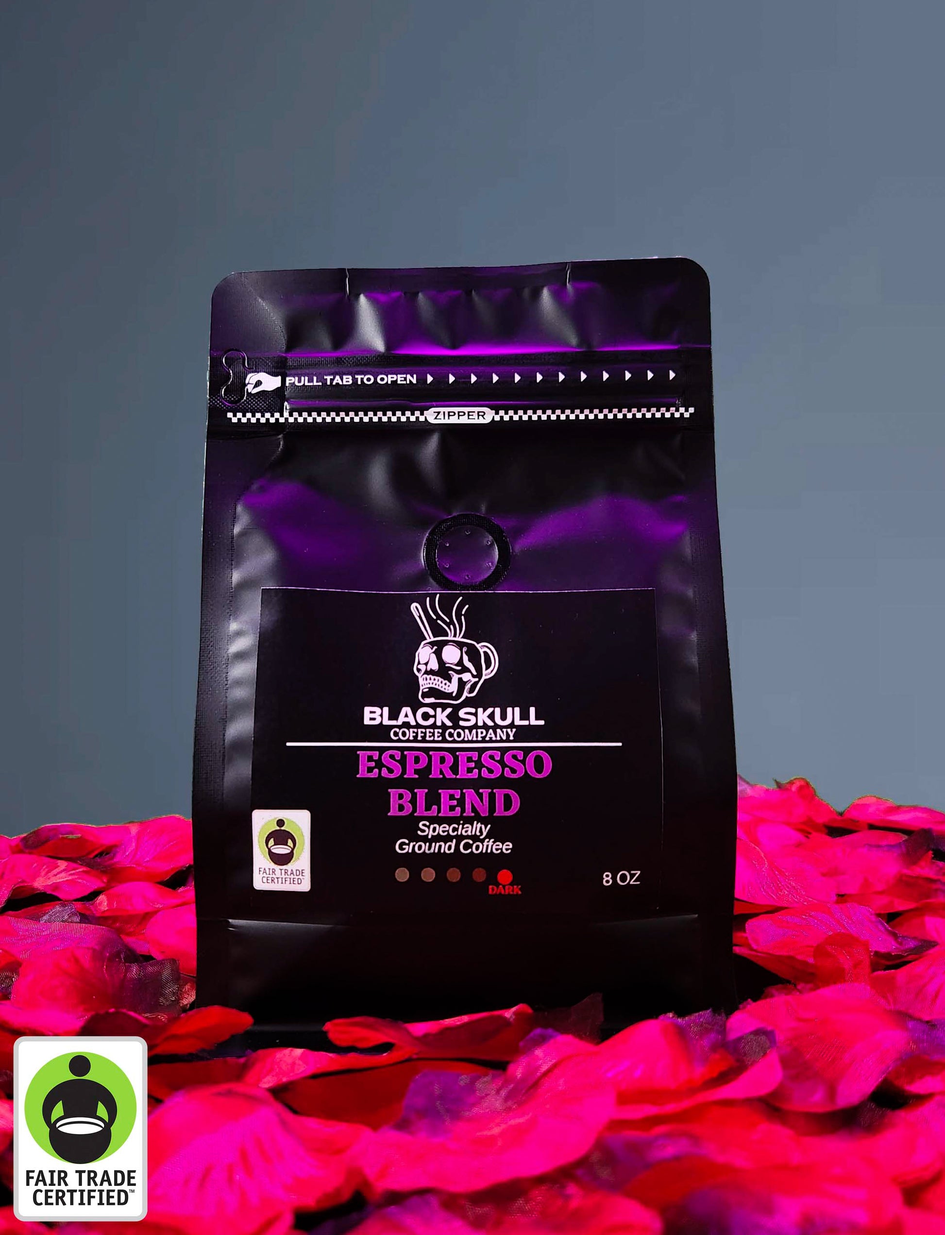 Black Skull Coffee Company Specialty Espresso Blend 8oz ground coffee package on a gray background with red rose petals and Fair Trade USA Logo.
