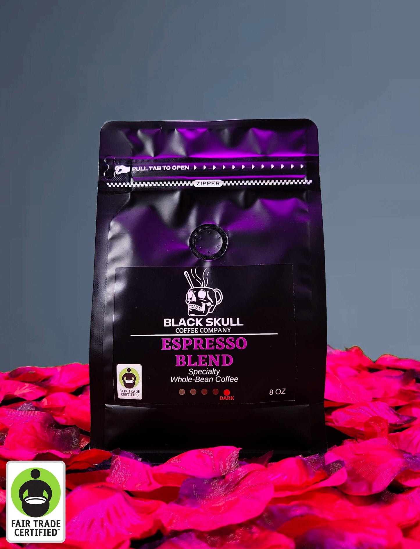 Black Skull Coffee Company Specialty Espresso Blend 8oz whole bean coffee package on a gray background with red rose petals and Fair Trade USA Logo.