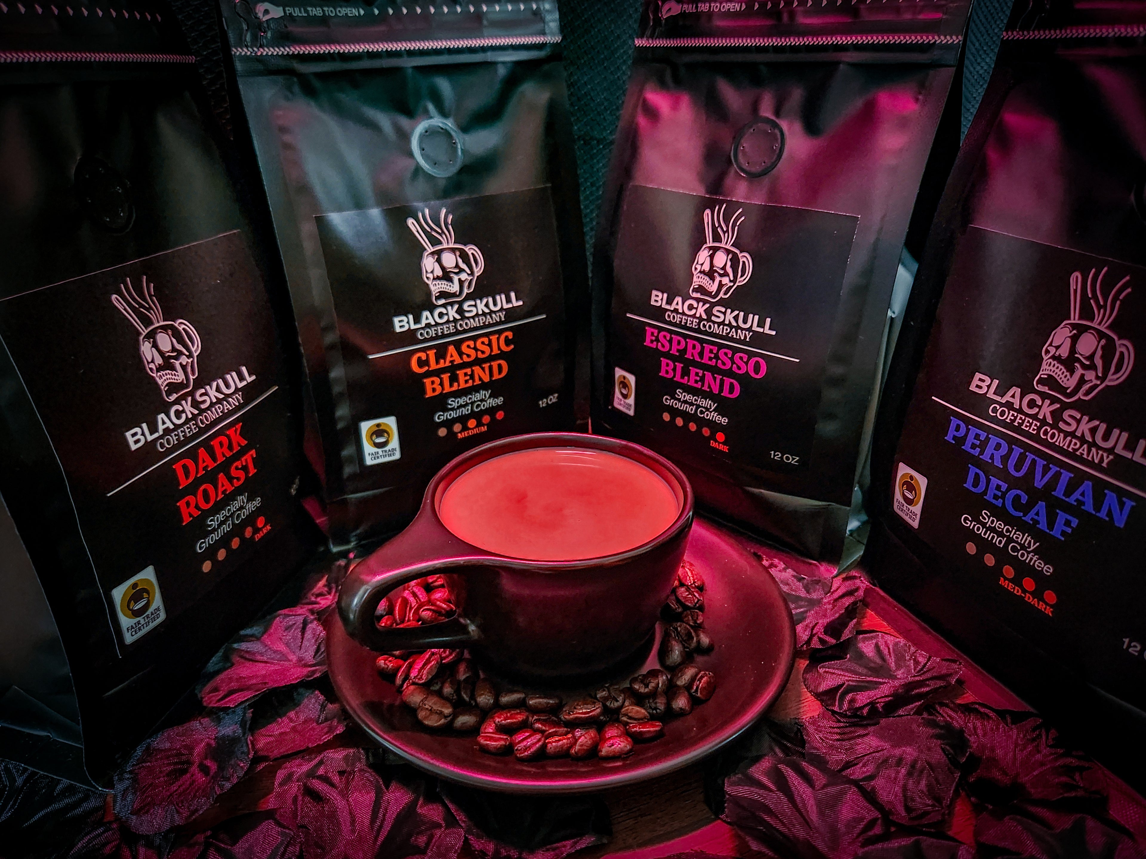 Black Skull Coffee Company coffee bags with a red cup and saucer on a dark background